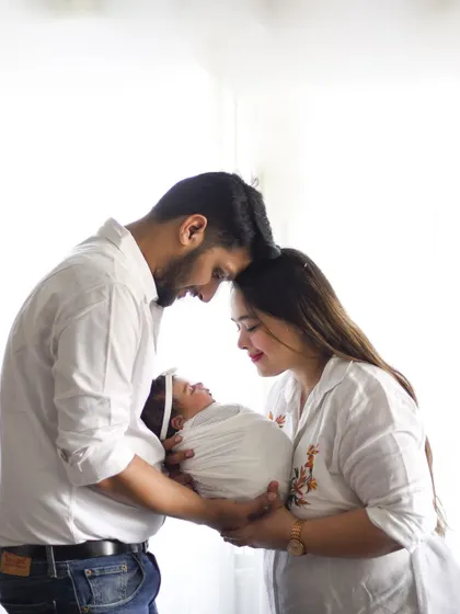 Foreheads touching, eyes closed, a moment of shared peace and joy. This pose beautifully captures the intimacy and connection between new parents and their baby.