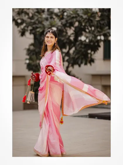 A happy bride in a pink saree, holding her traditional kalire.