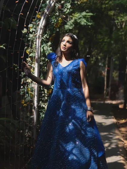 Another artistic shot of the blue sequin gown, showing its elegance and charm in a sun-dappled garden.