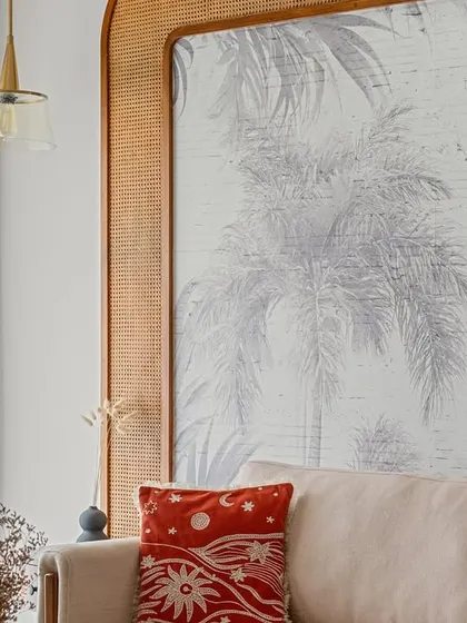 A detail shot of the living room, focusing on the custom cane-framed wallpaper feature. The pop of red from the cushion adds a touch of playful contrast to the neutral palette.