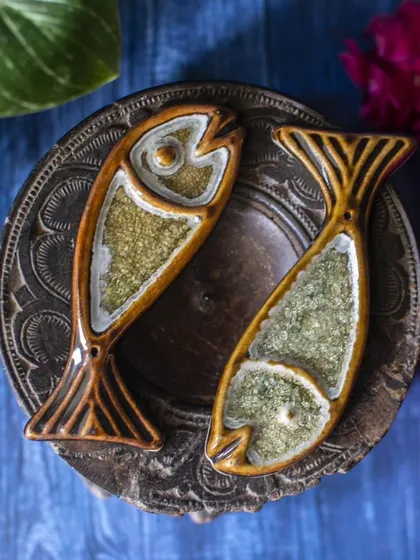 Another view of the brown and green fish incense holders, placed on a rustic wooden stand. This styling highlights their artisanal quality and how they can complement other natural decor elements.