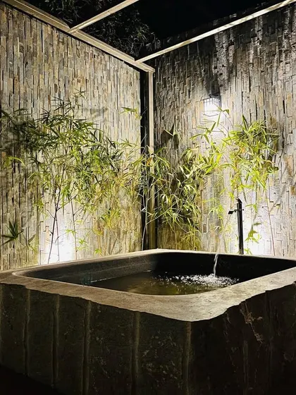 The play of light and shadow on the textured walls adds depth and character to this intimate outdoor bathroom.