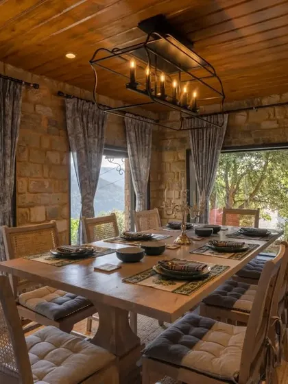 The dining room at Buransh Terraces, where meals are enjoyed with panoramic views of the mountains. The rustic stone walls and warm wood ceiling create a cozy, cabin-like feel.