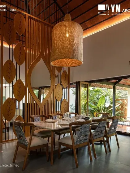 The dining room at Kuttiyil House, a testament to traditional architecture with its high ceiling, custom woodwork, and seamless connection to the outdoor spaces.
