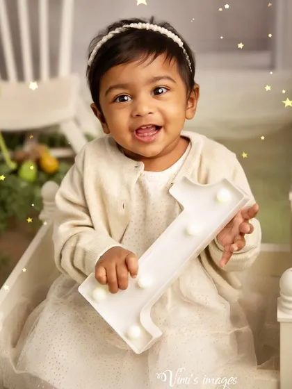 Proudly holding up the number one. This shot captures a key moment in a first birthday photoshoot, celebrating this major milestone with a bright, happy smile.
