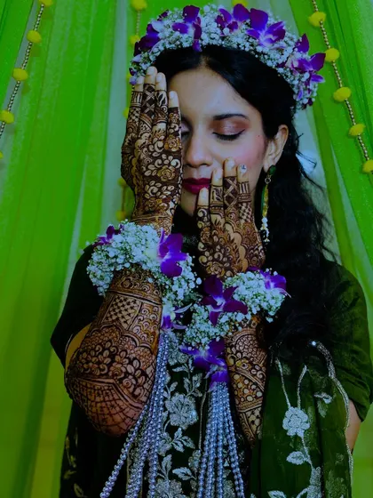 The bride covering her face with her henna-adorned hands, a classic and beautiful pose.