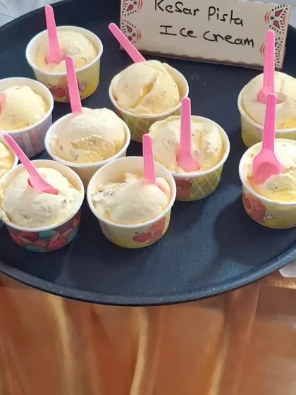 Scoops of delicious Kesar Pista ice cream served in cups, ready to be enjoyed by guests at a wedding.