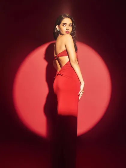 A spotlight moment for Anushka Sen in her red Elle List Awards gown. The dramatic lighting highlights the sleek silhouette of the dress.
