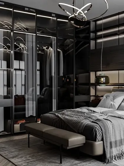 This master bedroom features a sleek, dark-themed design with a glass-fronted wardrobe that showcases a well-organized collection. The integrated lighting and minimalist furniture create a sophisticated and masculine space.