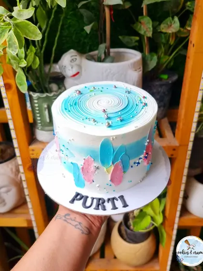 A fun and abstract cake with blue and pink brushstrokes. The swirl on top and the colorful sprinkles give it a playful and modern vibe.