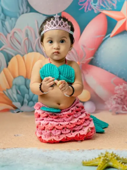 A sweet, direct-to-camera portrait of the baby in her mermaid outfit. The tiara adds a perfect touch of royalty to this fantasy photoshoot.