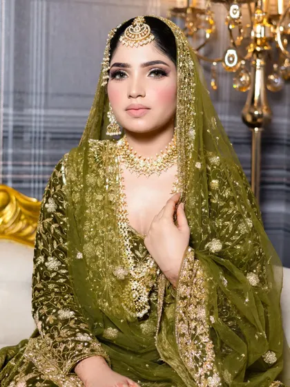 A regal bridal look featuring a stunning green dupatta. The makeup is kept elegant with defined eyes and a balanced complexion to complement the rich colors of the outfit.
