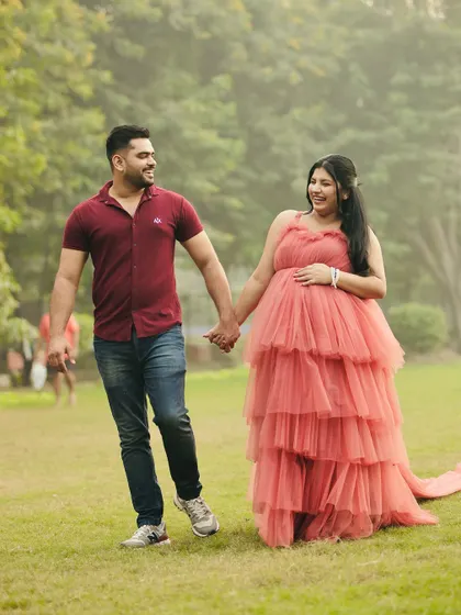 A happy stroll in the park. This couple's joy is infectious, and our rental gown adds a touch of elegance to their casual maternity shoot.