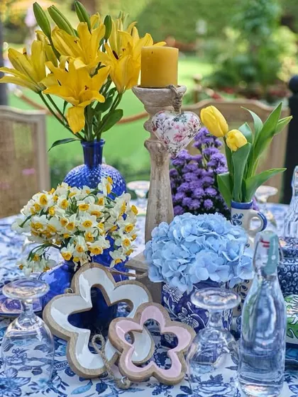 A stunning tablescape combining blue and white printed linens with bright yellow lilies and tulips, creating a cheerful and elegant look for a daytime lunch.