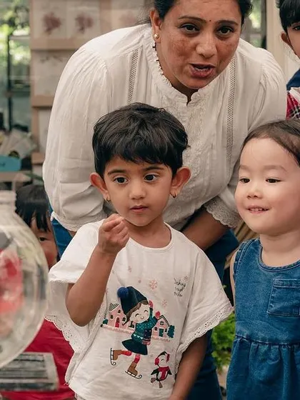 Children gather around a fishbowl at the nursery, fascinated by the swimming fish.