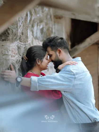 An intimate embrace against a stone wall, the couple lost in their own world.