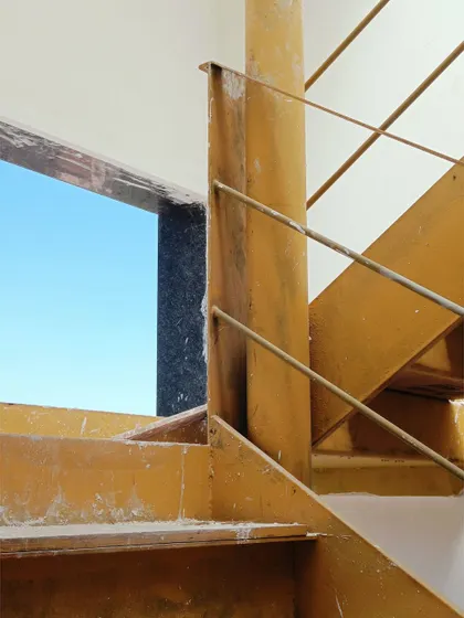 A detail of the custom-fabricated metal staircase at the Jayanagar Residence. The simple, clean lines of the steel and the warm tone of the wooden treads create a modern and functional design element.