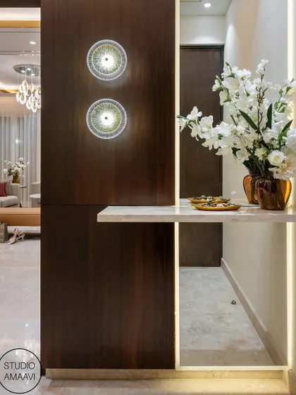 A detail shot of an entryway, where we combined a rich wood-paneled wall with a floating marble shelf. Integrated LED lighting and modern circular wall sconces turn this functional space into a beautifully lit architectural feature.