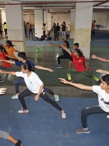A group of fencers in a deep lunge position during a training session. This foundational move is practiced relentlessly to build strength, flexibility, and perfect form.