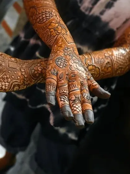 A close up on the hands of this bridal design, showing the intricate finger work and the dark, rich application of the henna paste.