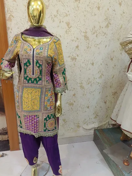 A mannequin display of a stunning multi-color embroidered suit. The patchwork design and rich colors make it a unique and festive piece.