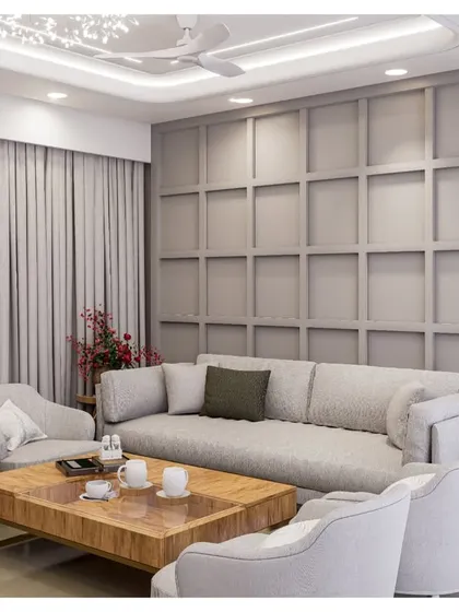 A living room with a sophisticated grey color palette. The wall features classic paneling, creating a timeless backdrop for the comfortable sofa and modern armchairs.