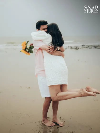 A joyful, candid moment of the couple embracing on the beach, capturing the fun and carefree spirit of their relationship.