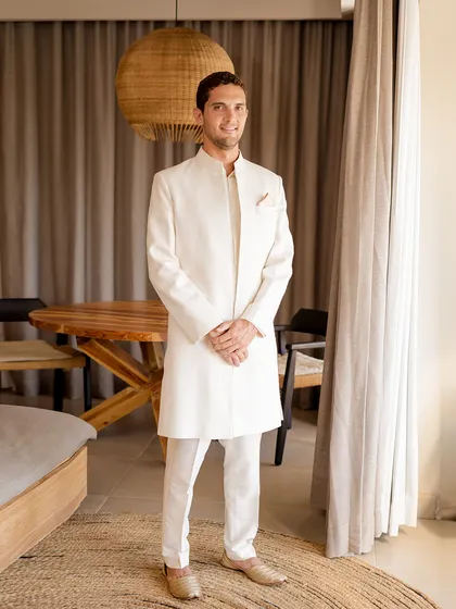 A picture of refined elegance. For this beach wedding, we styled the groom in a custom ivory sherwani by Lalit Laungani, a look that is both sophisticated and perfectly suited to the serene coastal setting.