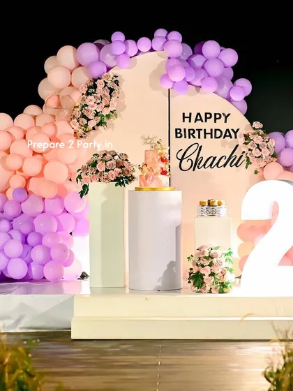 We specialize in large-scale, personalized decorations for milestone events like a 21st birthday. This outdoor setup features a custom-split arched backdrop, a pastel balloon garland, and large light-up marquee numbers to make the occasion feel extra special.