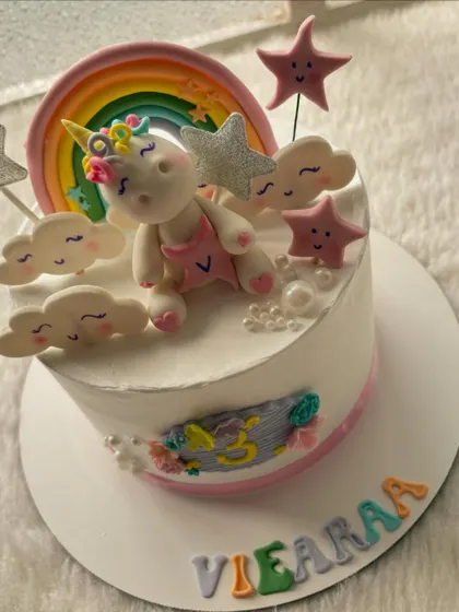 A dreamy unicorn cake with a cute, sleepy unicorn, a rainbow, and fluffy clouds. The pastel colors make it a perfect choice for a magical birthday.