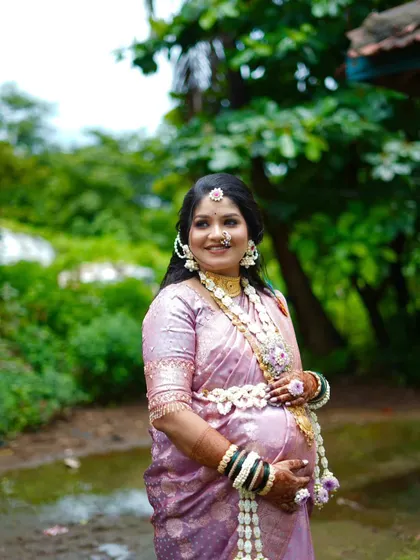 A smiling mom-to-be wearing a floral kamarband (waistband) and necklace set. I design these pieces to be comfortable and adjustable for the perfect fit.