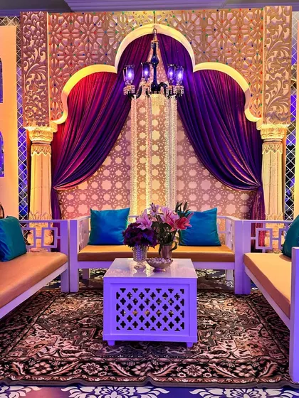 The seating lounge is framed by grand arches and purple drapes, with a patterned backdrop and a traditional rug completing the authentic Turkish feel.