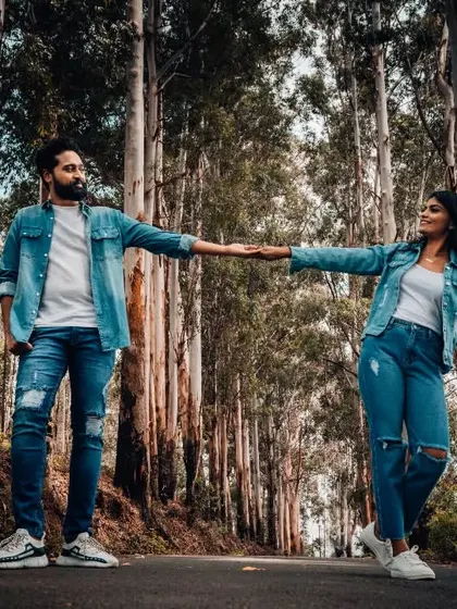 A creative pre-wedding shot of a couple holding hands, separated by a path in a forest, symbolizing their individual paths now joining as one.