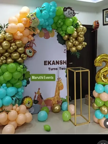 A modern jungle theme for Ekansh's second birthday, using a stylish arch of retro-colored balloons in green, gold, and peach, complete with a backdrop and animal figures.