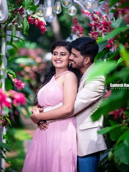 A candid and joyful moment of a couple laughing and embracing in a garden.