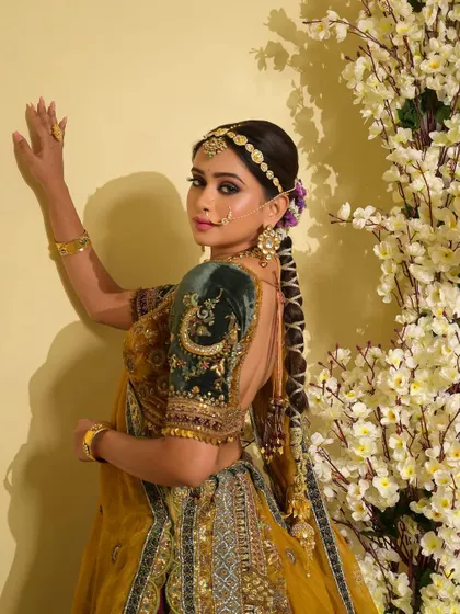 This side profile highlights the intricate hairstyle and the elegant drape of the dupatta. The makeup is kept subtle and clean to balance the richness of the outfit and heavy jewelry.