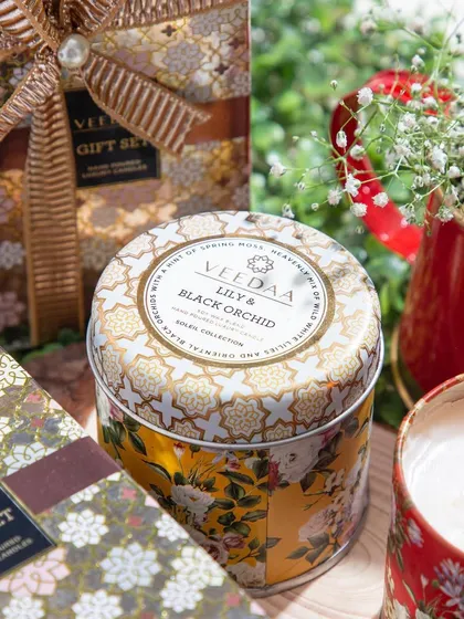 Our Lily & Black Orchid three-wick tin candle, shown with its elegant gift box. Each candle is hand-poured with toxin-free soy wax and infused with fragrant essential oils, making it a beautiful and thoughtful gift.