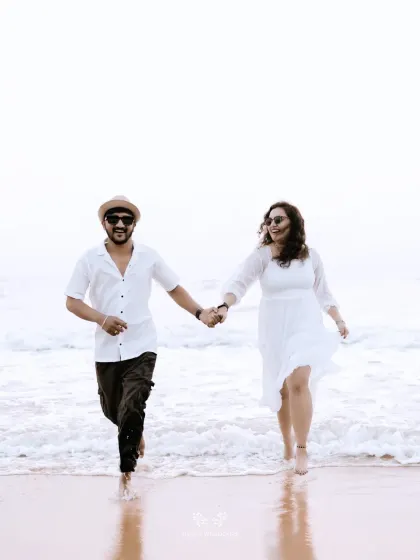 A joyful shot of the couple running hand-in-hand out of the ocean waves.