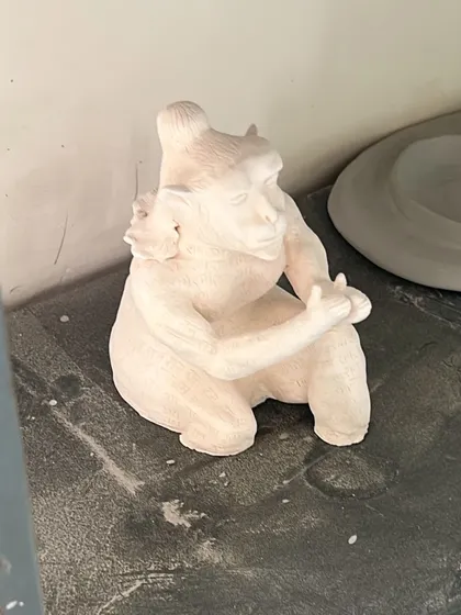 The Hanuman sculpture after its first firing (bisque firing). At this stage, the clay has turned white and is hard but still porous, ready for glazing or final touches.