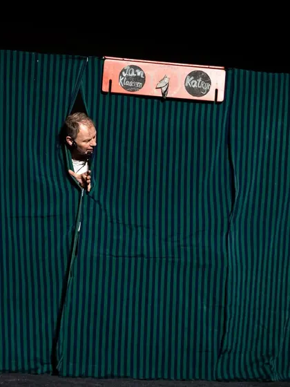 The puppeteer peeks through the curtains of his booth, a classic trope in this style of interactive hand puppet theatre.