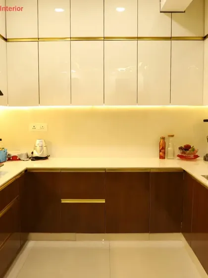 A full view of a U-shaped kitchen we designed. The combination of dark wood lower cabinets and glossy white upper cabinets with gold trim creates a look of timeless elegance.