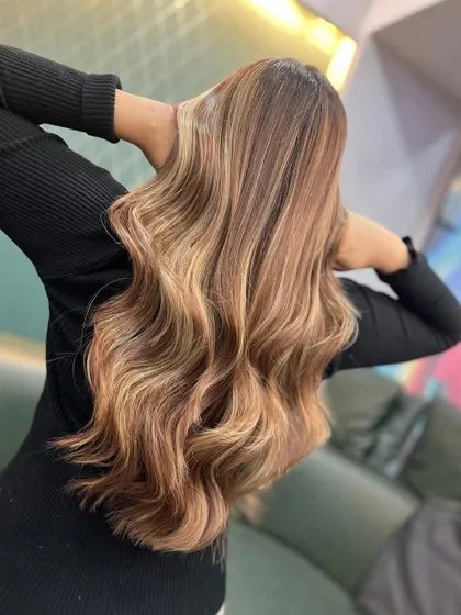 The back of this warm brownish-blonde look, showing the full extent of the beautiful balayage and soft waves.