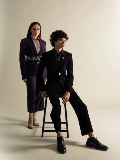 A full-length dual-model shot for a formal wear brand. The composition is classic and elegant, showcasing the tailored suits.