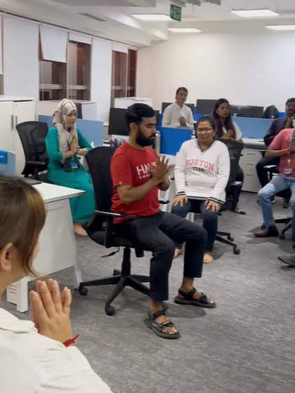 Leading a group of DNATA employees in a seated centering exercise. My chair yoga sessions are interactive and ensure everyone feels engaged and supported.