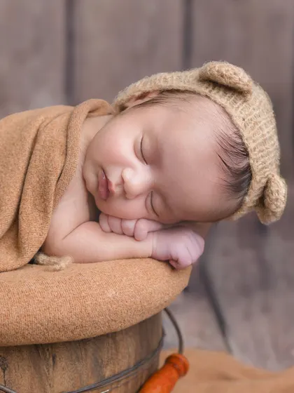 A simple, beautiful close-up of the baby in the bear hat, focusing on their peaceful, sleeping face.
