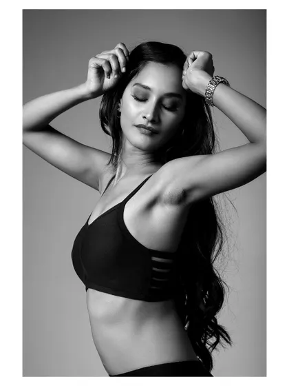 A powerful black and white fitness portrait. The lighting emphasizes the model's strength and athletic form.