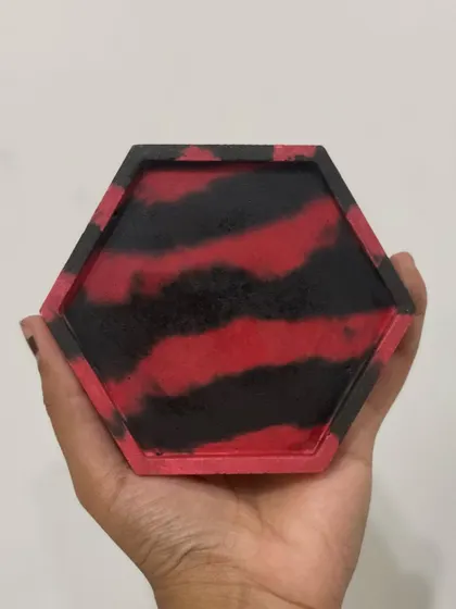 A close-up of one of the 'Ferrari' inspired coasters, showing the vibrant red and black marbled pattern.
