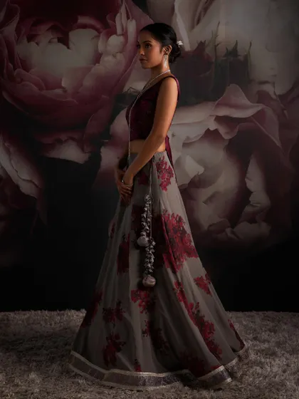 Experience the perfect blend of elegance with this grey lehenga featuring bougainvillea prints and a deep red velvet blouse, ensuring you capture attention with every look.