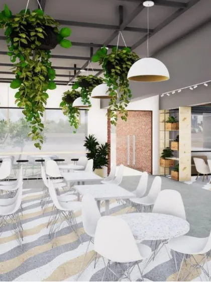 This view of the JIM Jaipur canteen highlights the open, airy feel created by the high ceiling, hanging plants, and light color palette, making it a pleasant space for students to gather.