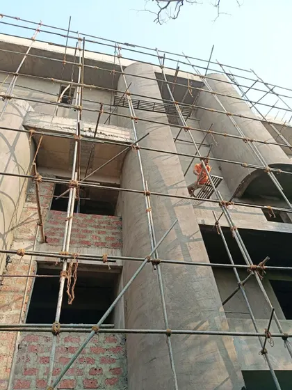 An artisan at work on the facade of The Nest. This photo highlights the human element in construction, as skilled labor is essential to executing the complex curves and smooth finishes of the building's design.